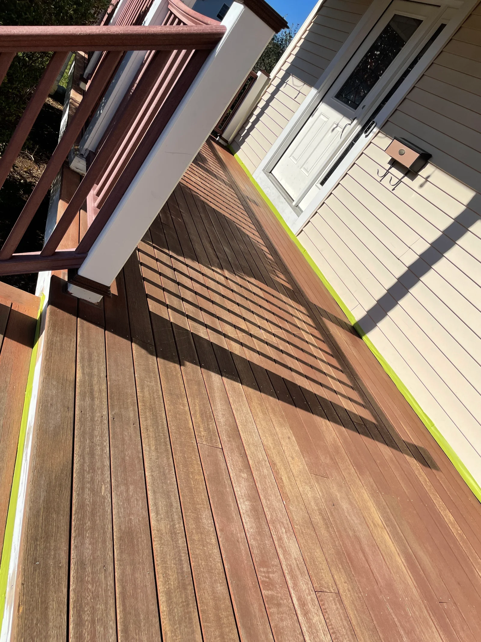 Pressure-washed composite deck with restored wood tones and yellow safety tape border
