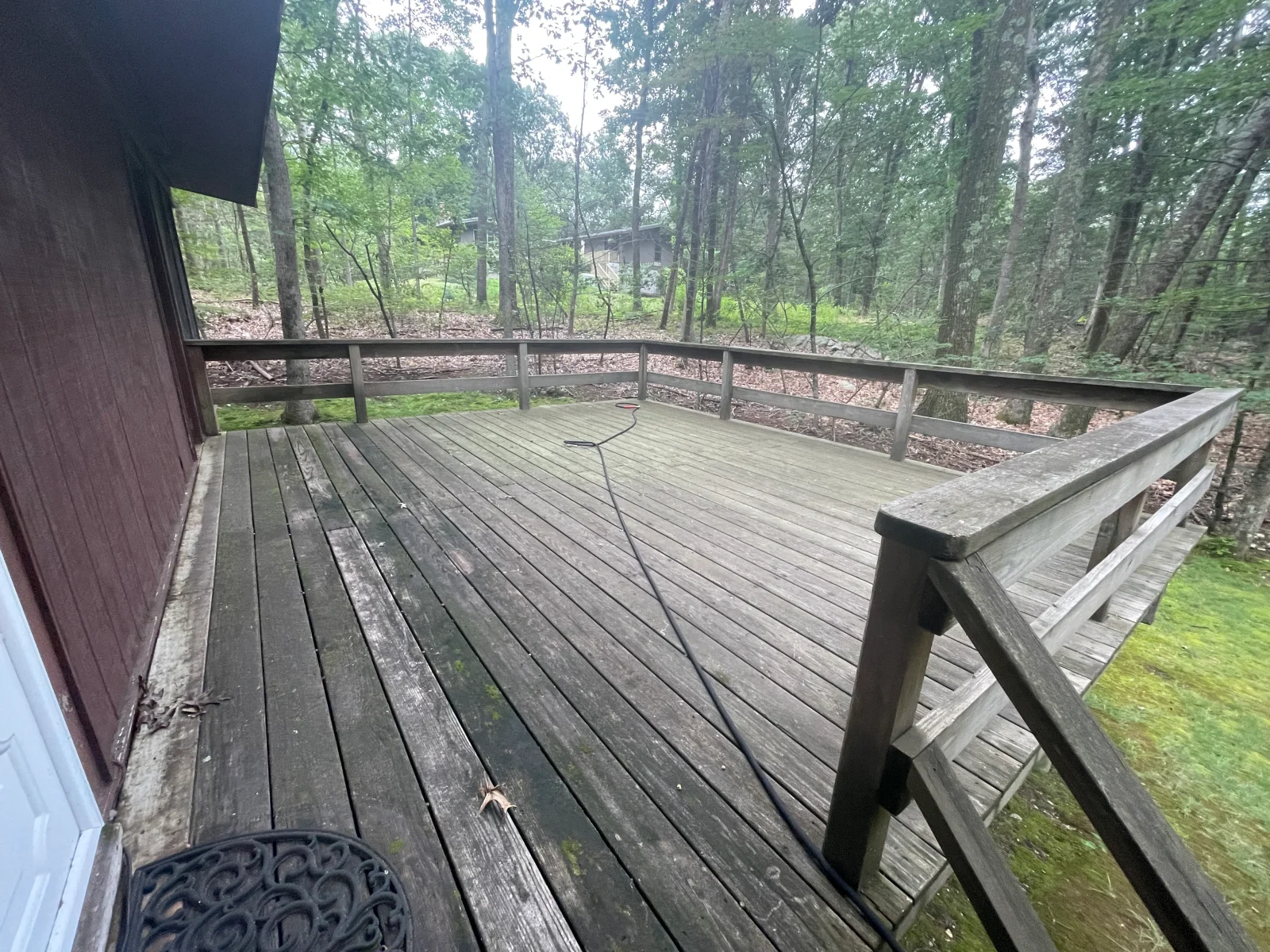 Pressure-washed composite deck with metal railings and bench seating in wooded setting