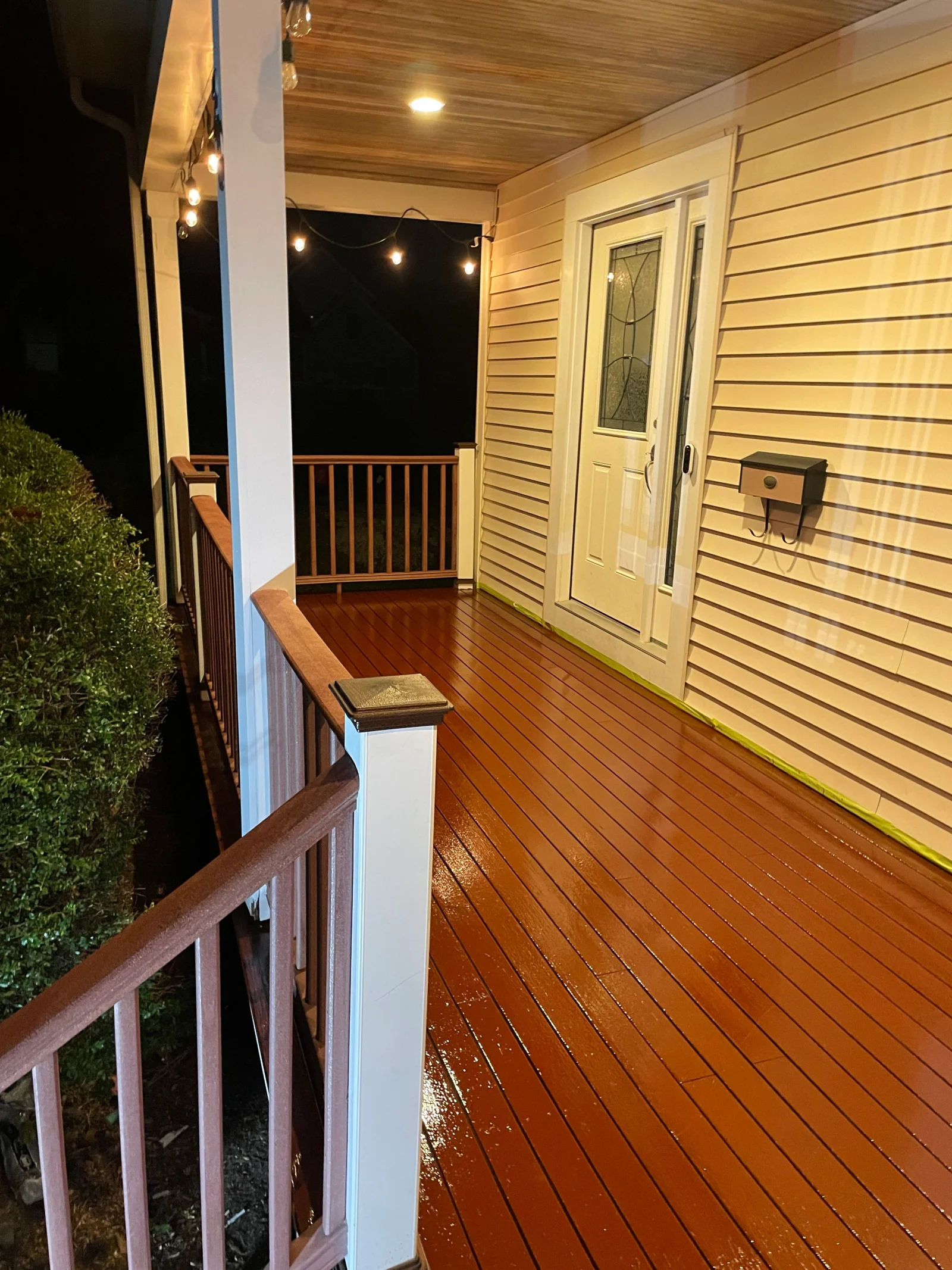 Pressure-washed composite deck with string lights and recessed lighting on covered porch
