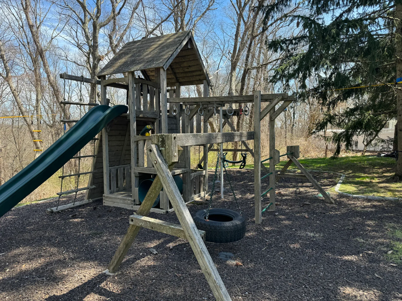 Wooden playground tower with slide and climbing equipment after pressure washing